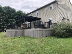 Timbertech PVC Castle Gate with matching skirting underneath, black Timbertech Radiance rails with cap lights, black composite pergola with stone pillars &#8211; Chester County PA