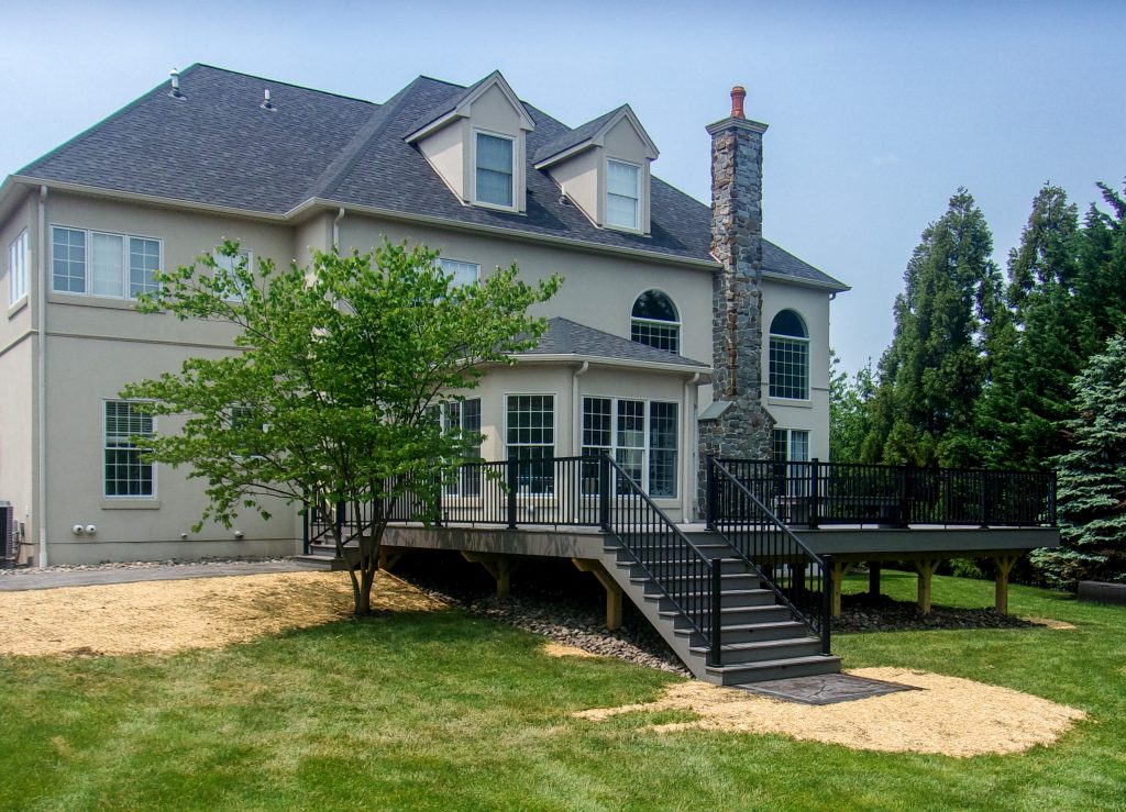 Front view of a new PVC gray deck with matching stairs and black railings.