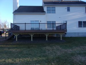 Azek Mahogany deck with black Aluminum railings, under deck landscaped with weed blocker fabric and stones